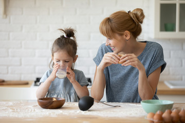 Happy mom and little daughter enjoy weekend in home kitchen