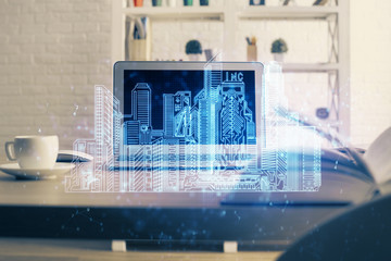 Desktop computer background in office and big town buildings hologram drawing. Double exposure. Smart city concept.