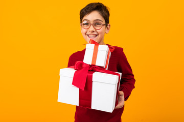 smiling boy in a red jumper with two box of a gift for Valentine's day on a yellow background