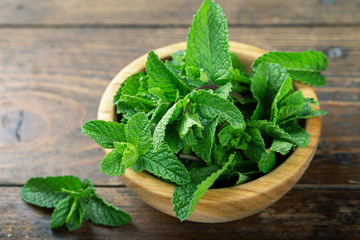 Fresh mint in a plate on a wooden background. decor for refreshing drinks and desserts.
