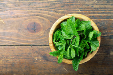 Fresh mint in a plate on a wooden background. decor for refreshing drinks and desserts.