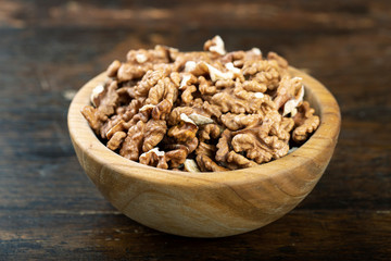 Peeled walnut in a wooden bowl .