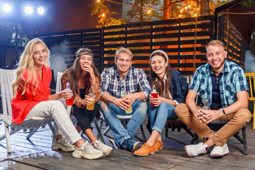 Naklejka na ściany i meble Young caucasian friends which enjoying time together on party at summer evening. Weekend, summer nights and lifestyle concept.