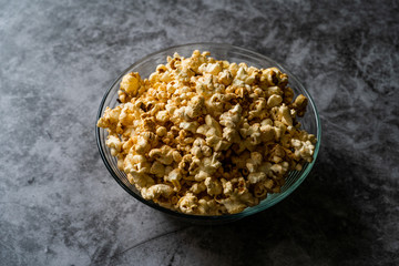 Caramel Popcorn in Glass Bowl on Grey Surface.