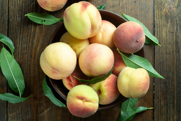 Ripe peaches in  plate on wooden background.