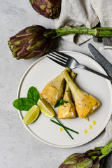 artichoke with olive oil, lemon and spices. typical Italian appetizer.  fresh and healthy artichoke plant. seasonal dish on a white craft plate. Italian cuisine recipe. selective focus