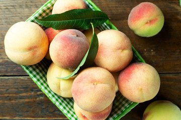 Ripe peaches in basket on wooden background