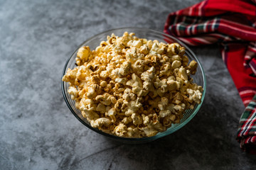 Caramel Popcorn in Glass Bowl on Grey Surface.