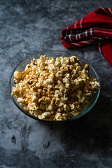 Caramel Popcorn in Glass Bowl on Grey Surface.