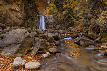 Long exposure view of the beautiful Pruncea–Caşoca Waterfall with fallen leaves in an autumn landscape,Siriu, Buzau, Romania