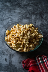 Caramel Popcorn in Glass Bowl on Grey Surface.
