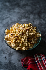 Caramel Popcorn in Glass Bowl on Grey Surface.