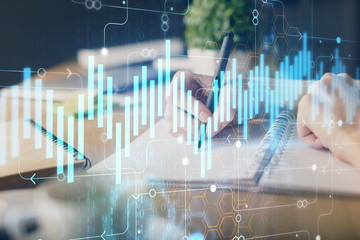 Financial forex graph drawn over hands taking notes background. Concept of research. Multi exposure