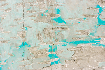 Scratched broken concrete wall with blue paint and stucco chips and cracks. Rough uneven abstract texture