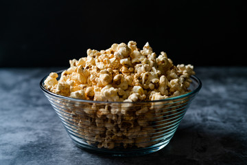 Caramel Popcorn in Glass Bowl on Grey Surface.