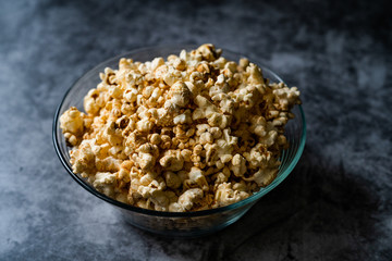 Caramel Popcorn in Glass Bowl on Grey Surface.