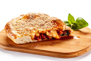 Pizza calzone on cutting board on white background