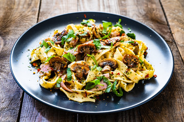 Tagliatelle with ham and chmpignon wooden table