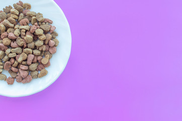 A bowl of cat food on a lilac background. The view from the top