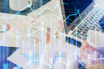 Obraz premium Double exposure of stock graph with businessman typing on computer in office on background. Concept of hard work.