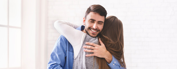 Happy couple in love embracing indoors, man and woman hugging tightly