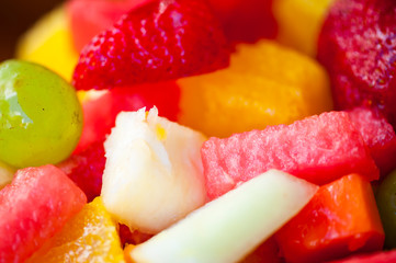 Fototapeta na wymiar Close-up of tropical fruit salad featuring brightly colored watermelon, pineapple, grape, cantaloupe, strawberry, and orange slices