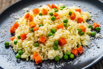 Risotto with carrot and grean peas on wooden background