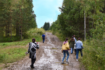 A group of people walking up a mountain forest road on a summer morning