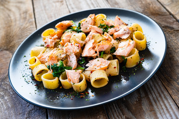 Pasta with salmon and spinach on wooden background