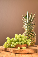 Fototapeta na wymiar green grapes and pineapple on a wooden board