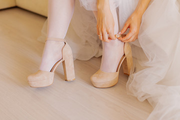Young bride closes shoes on a happy wedding day.