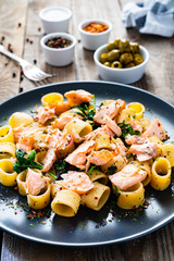 Pasta with salmon and spinach on wooden background