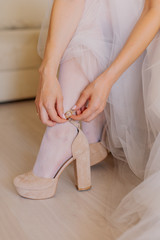 Young bride closes shoes on a happy wedding day.