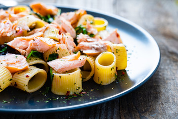 Pasta with salmon and spinach on wooden background