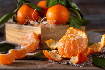 whole tangerine on the skin, Mandarin slices, a box of ripe tangerines with green leaves on a wooden