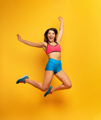 Fototapeta na wymiar Sport woman jumps on a yellow background. Happy and joyful expression.
