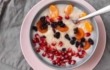 porridge with Mandarin slices, pomegranate seeds, raisins, dried apricots, top view,plate of porridge with Mandarin slices, pomegranate seeds, raisins, dried apricots, top view