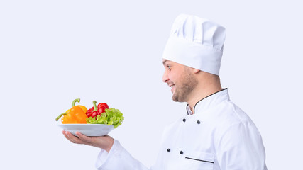 Chef Holding Plate With Vegetables Over White Background, Panorama, Side-View