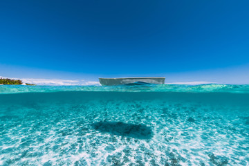 Fototapeta na wymiar Tropical ocean water with sandy bottom and boat