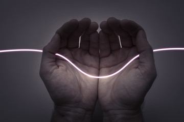 Neon Light Thread - Wire in Open Hands on Dark Background. Creativity and Energy Concept.
