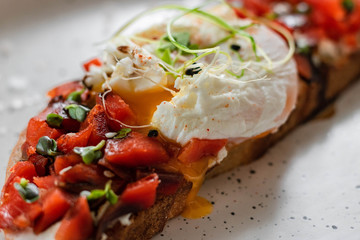 Sandwich with red fish, poached egg, balsamic vinegar and micro-greens