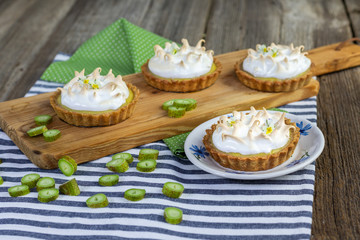 Tartlets with sour rhubarb filling and meringue on old wood table