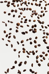 Falling grains of roasted coffee on a white background