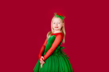 Beautiful little plump girl princess dancing in luxury green dress isolated on red background. Carnival party with costumes