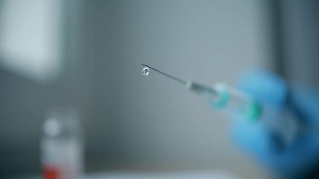 Slow motion shot of a dripping syringe