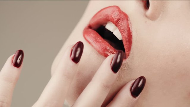 Close up red lipstick and red nails.  Perfect skin. Concept lip gloss. Decorative cosmetics.