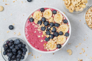 Healthy breakfast bowl: berry smoothie with banana, blueberries, granola and cashew. Summer dessert