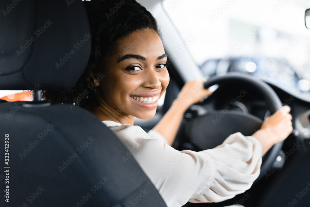 Wall mural woman buying new car doing test drive in dealership store