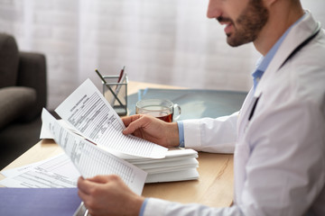 Dark-haired bearded doctor in a white robe looking involved