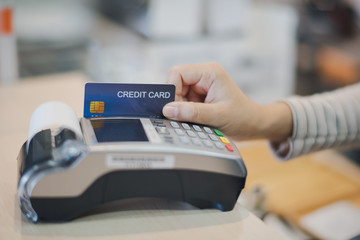 Hand of young woman seller using card reader for payment of a credit card. Accept payment by credit card technology at retail shop. Cashless Payment concept.
